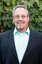 A portrait of a man with glasses and a suit jacket