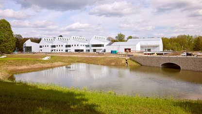 A large, white building in the background and behind a pond and bridge.